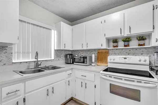 a kitchen with granite countertop white cabinets and white appliances