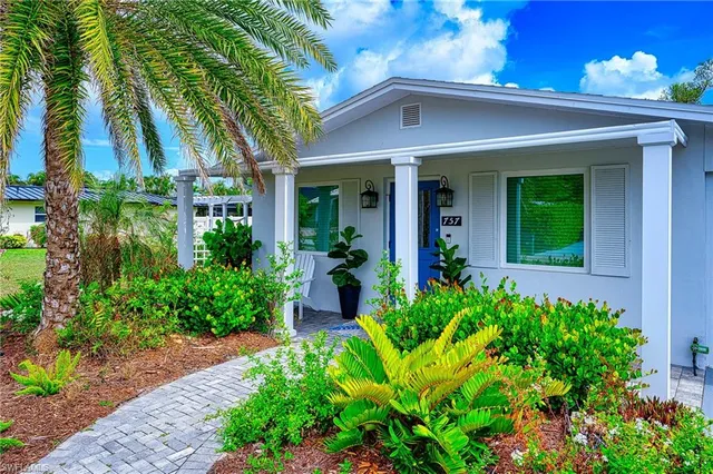 a view of a house with potted plants and a flower garden
