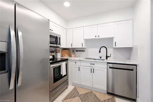 a kitchen with stainless steel appliances granite countertop a sink a stove a refrigerator and cabinets