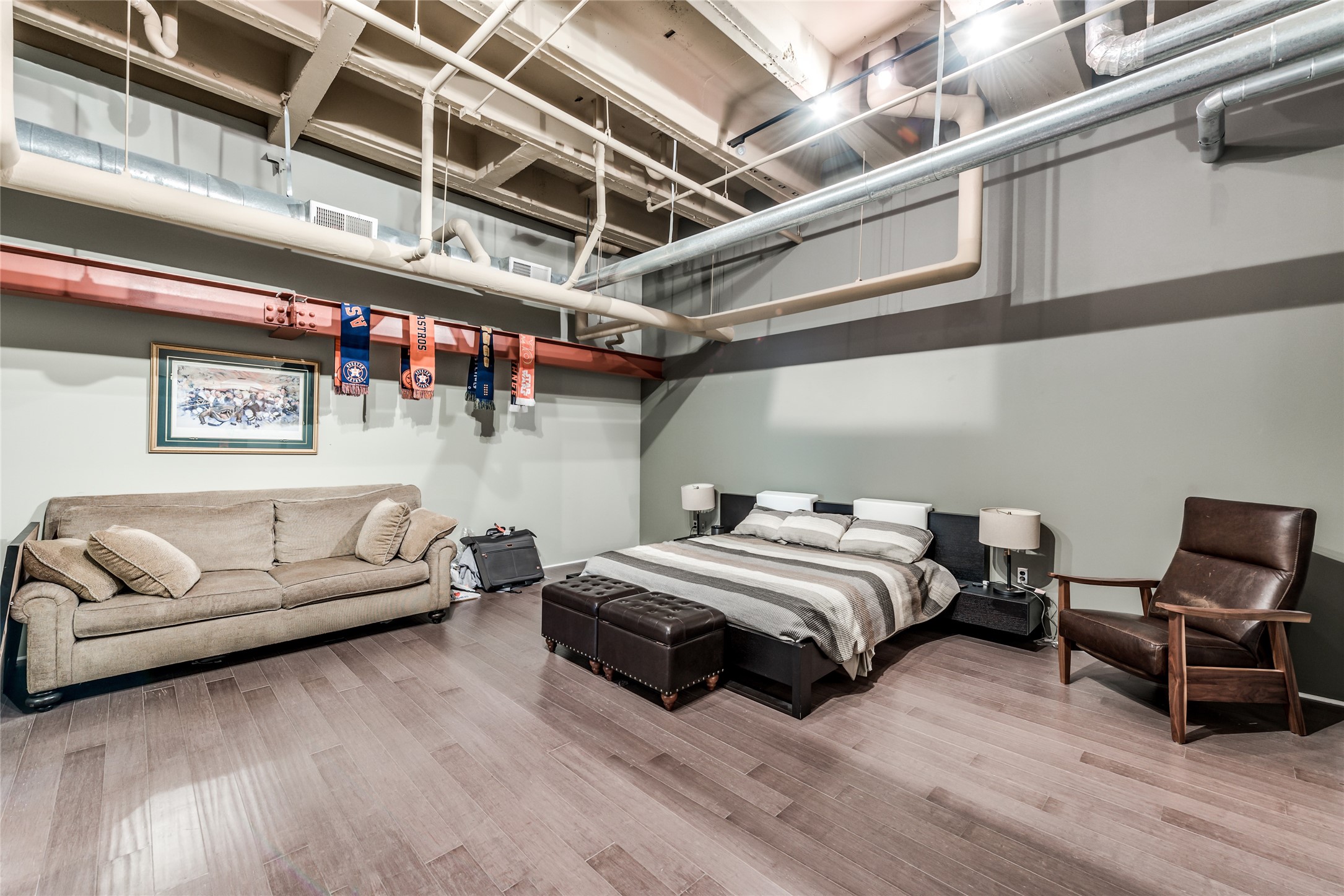 705 Main Street, Unit 215 Houston, TX 77002 - Photo 22 of 36 This loft-style primary bedroom features exposed ductwork and beams for an industrial feel.