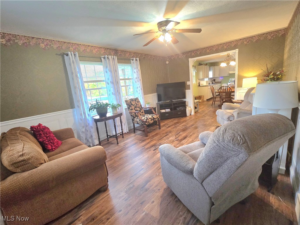 8019 Kroft Road Mount Perry, OH 43760 - Photo 16 of 41 Living room featuring wallpapered walls, wainscoting, wood finished floors, and a ceiling fan