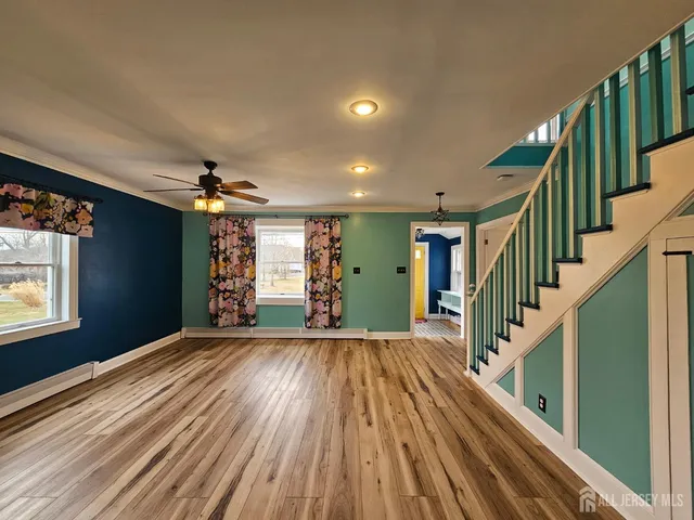 a view of an empty room with wooden floor a ceiling fan and window