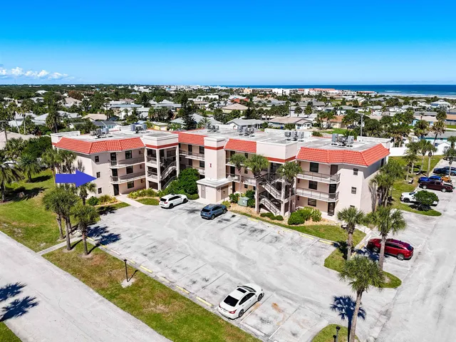 an aerial view of a city with lots of residential buildings ocean and mountain view in back