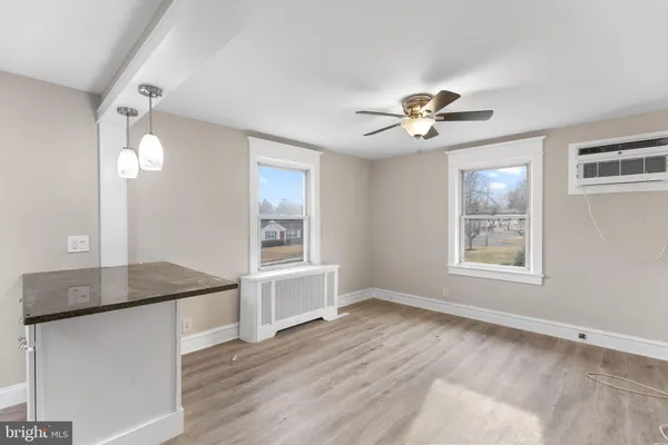 a view of an empty room with a window and a kitchen