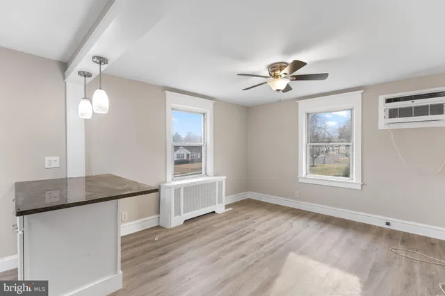 a view of an empty room with a window and a kitchen