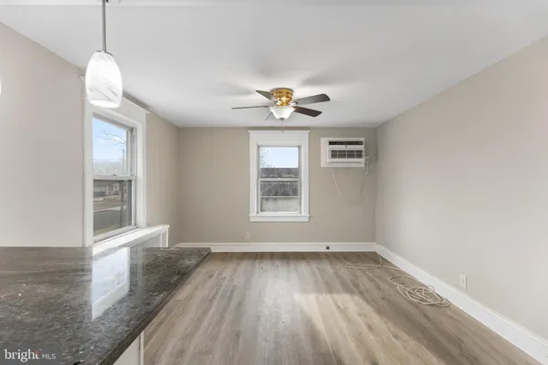 an empty room with wooden floor chandelier fan and windows