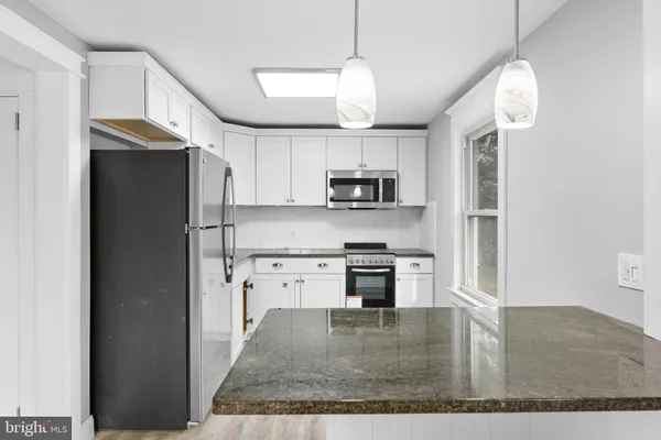 a kitchen with kitchen island a counter space a sink appliances and cabinets