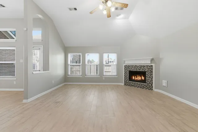 a view of an empty room with wooden floor and a fireplace