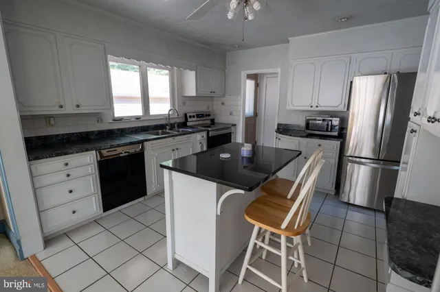 a kitchen with granite countertop a refrigerator a stove top oven and cabinets