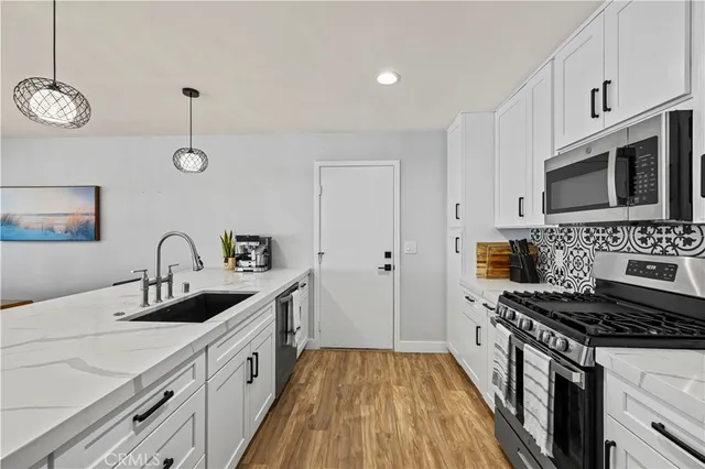 a kitchen with stainless steel appliances granite countertop a sink dishwasher a stove and a refrigerator with wooden floor