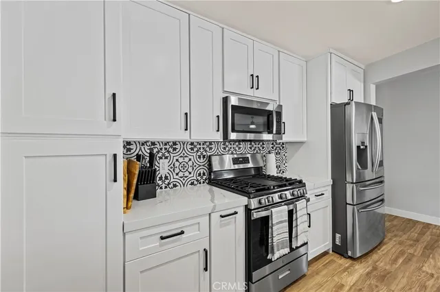 a kitchen with white cabinets and stainless steel appliances