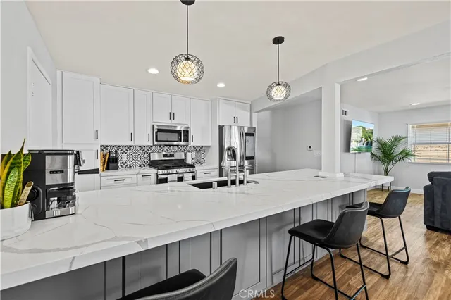 a kitchen with stainless steel appliances kitchen island granite countertop a dining table chairs stove refrigerator and cabinets