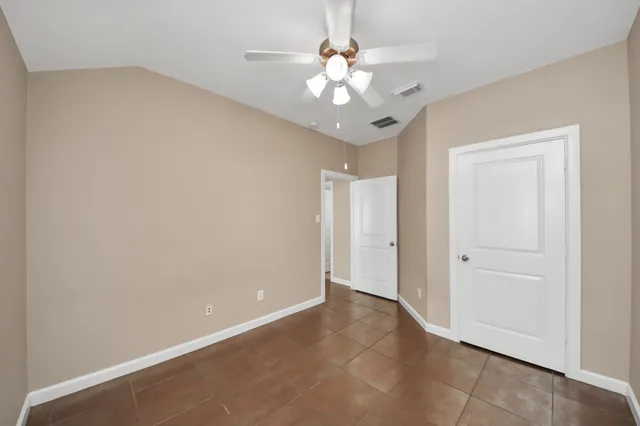 an empty room with a chandelier fan and a ceiling fan