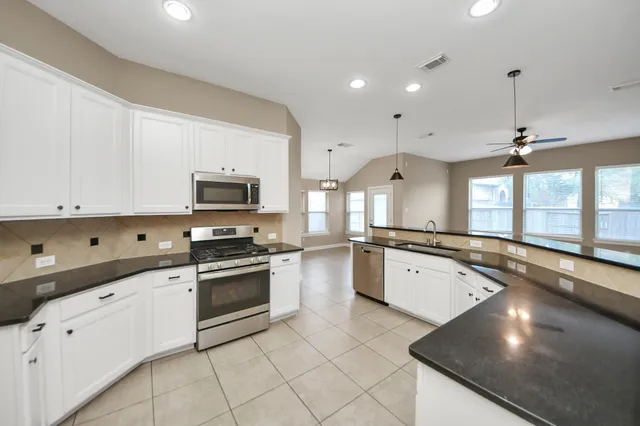 a kitchen with granite countertop a sink stainless steel appliances and cabinets