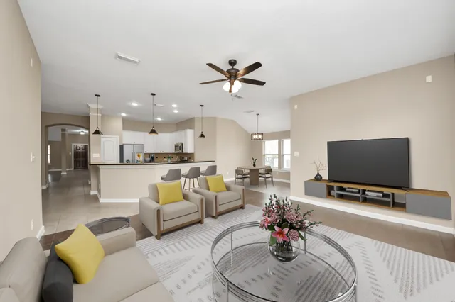 a living room with furniture a flat screen tv and a chandelier