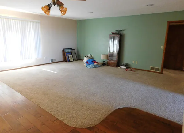 an empty room with windows and ceiling fan