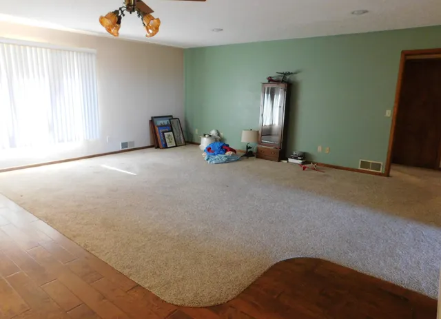 an empty room with windows and ceiling fan