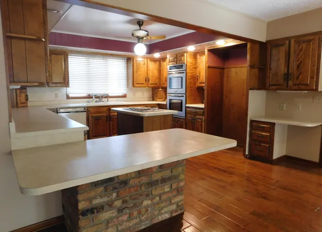 a kitchen with stainless steel appliances granite countertop a refrigerator a sink dishwasher a stove with wooden floor and cabinets