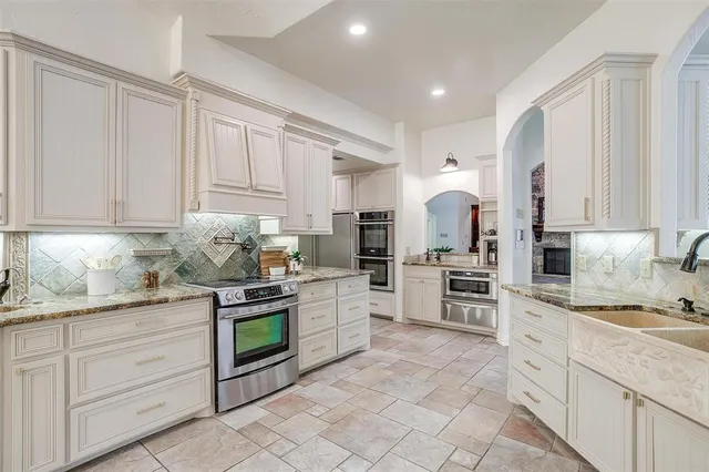 a kitchen with granite countertop white cabinets and stainless steel appliances