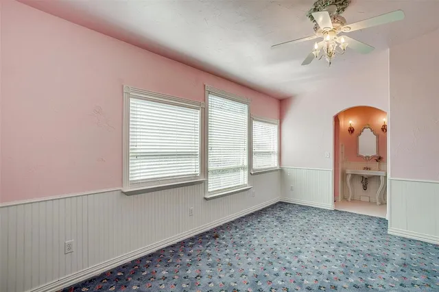 an empty room with chandelier fan and windows