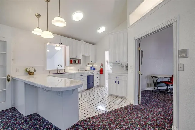 a large white kitchen with a sink stainless steel appliances and cabinets