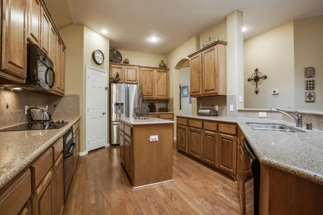 a kitchen with stainless steel appliances granite countertop a sink a stove refrigerator and cabinets