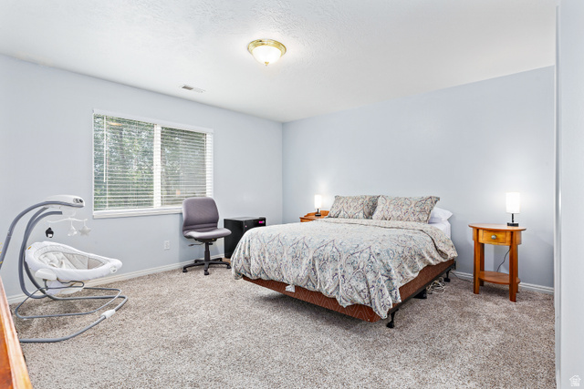148 South Ridgeview Drive Orem, UT 84058 - Photo 16 of 23 Carpeted bedroom featuring a large window with blinds, light blue painted walls, and a ceiling-mounted light fixture