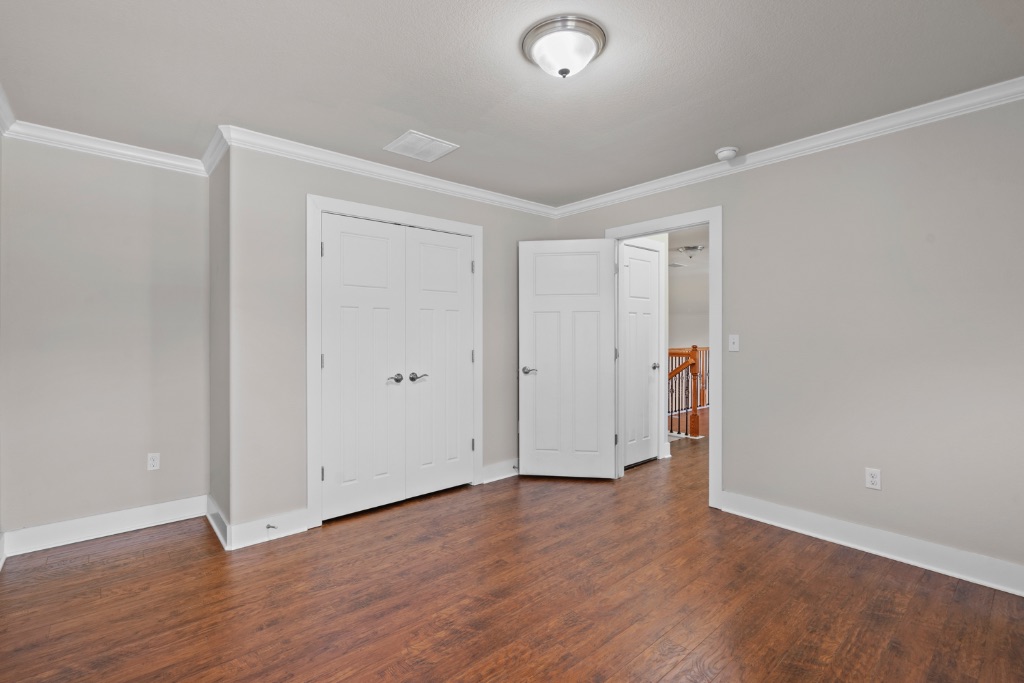 11229 Avery Station Loop, Unit 36 Austin, TX 78717 - Photo 28 of 37 Unfurnished bedroom with ornamental molding, dark wood-type flooring, and a closet