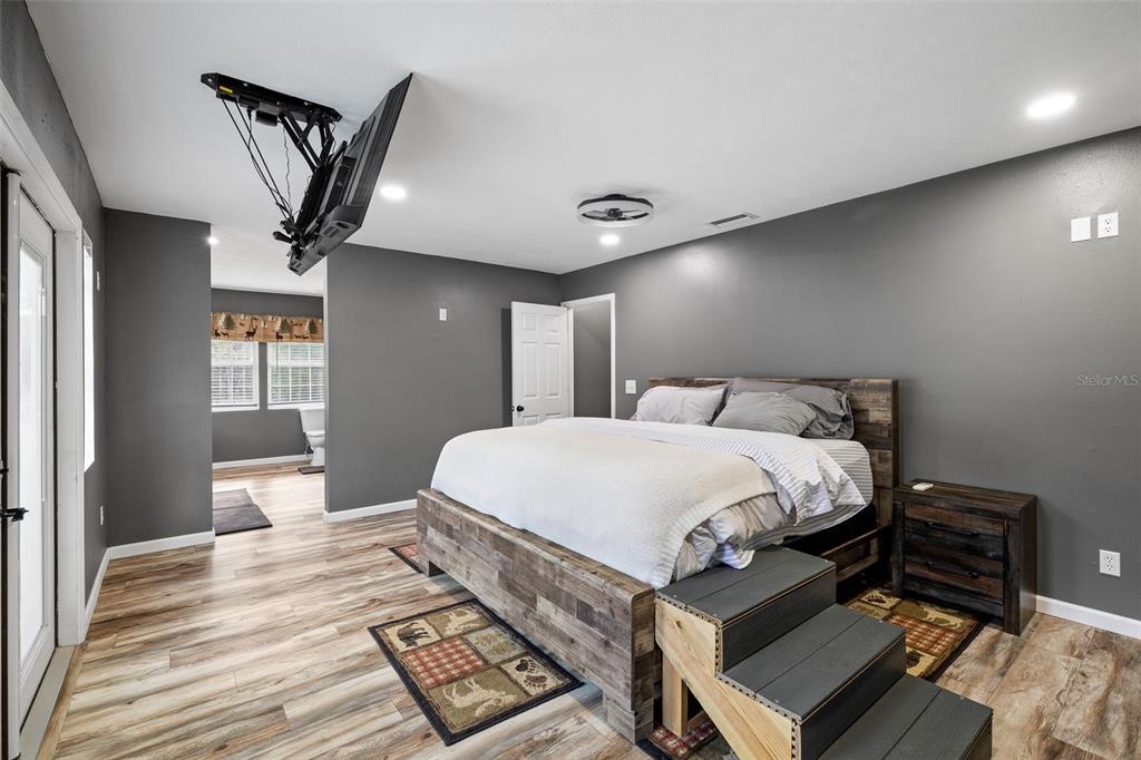 11311 Northeast 40th Street Road Silver Springs, FL 34488 - Photo 28 of 67 a spacious bedroom with a bed a rug and wooden floor