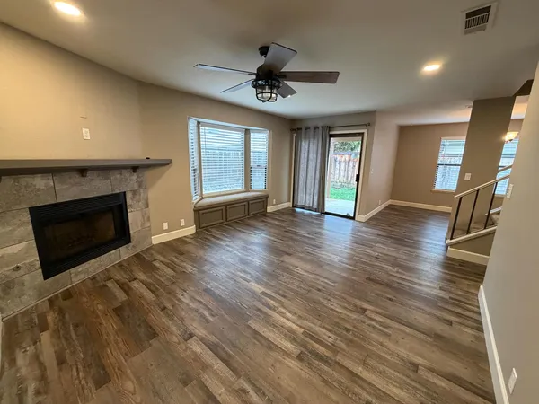 an empty room with wooden floor a fireplace and windows