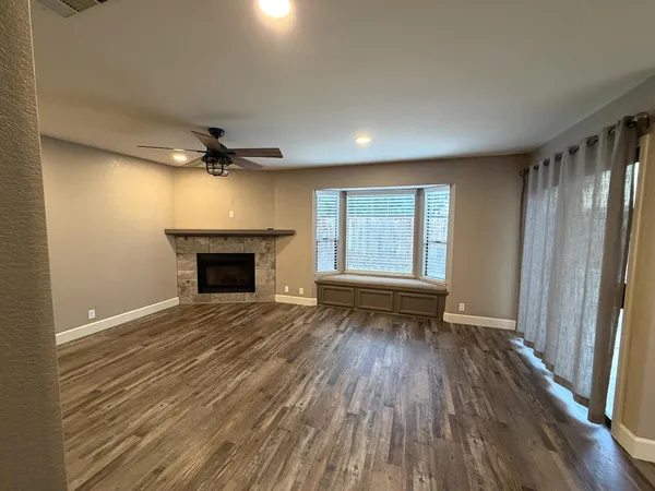an empty room with wooden floor fireplace and windows