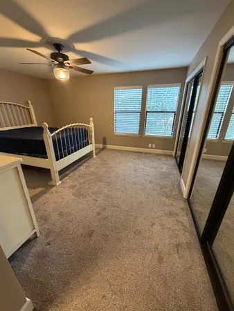 an empty room with windows and a ceiling fan