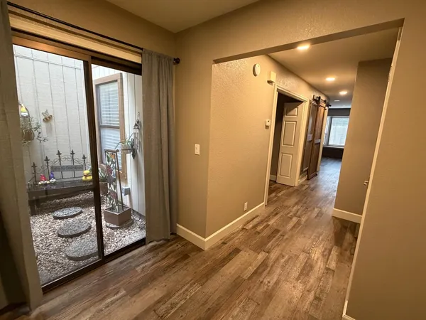 a view of a hallway with wooden floor and a bathroom