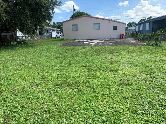 a view of a white house with a yard and sitting area