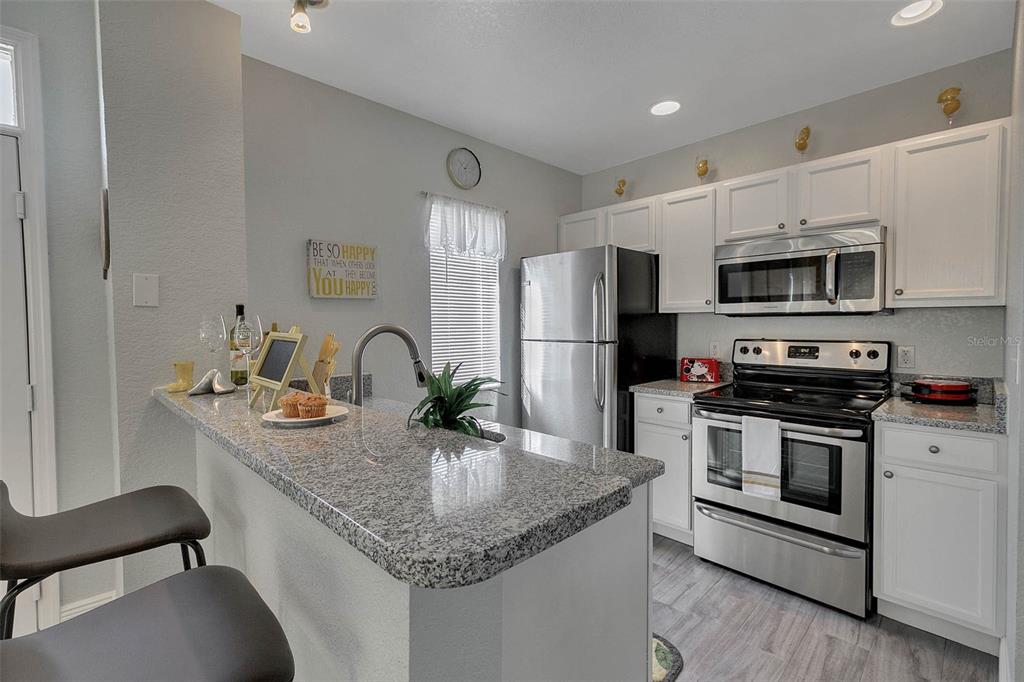 4561 Yellowgold Road East, Unit 102 Kissimmee, FL 34746 - Photo 2 of 12 a kitchen with stainless steel appliances granite countertop a sink stove and refrigerator