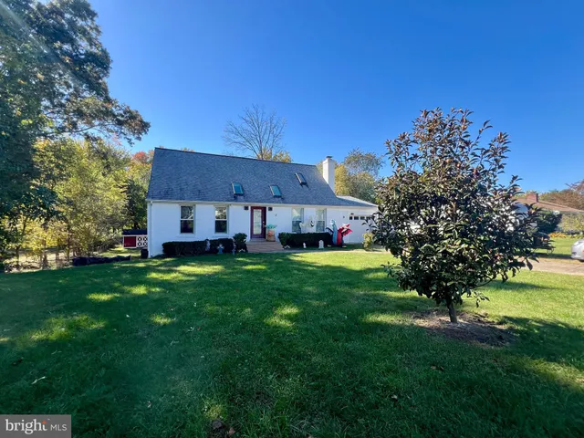 a view of a house with a big yard potted plants and large tree