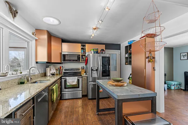 a kitchen with stainless steel appliances granite countertop a sink refrigerator and cabinets