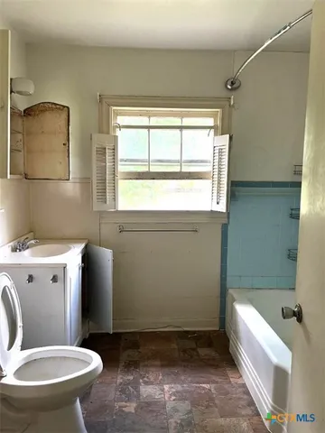 a bathroom with a granite countertop toilet a sink and a bathtub