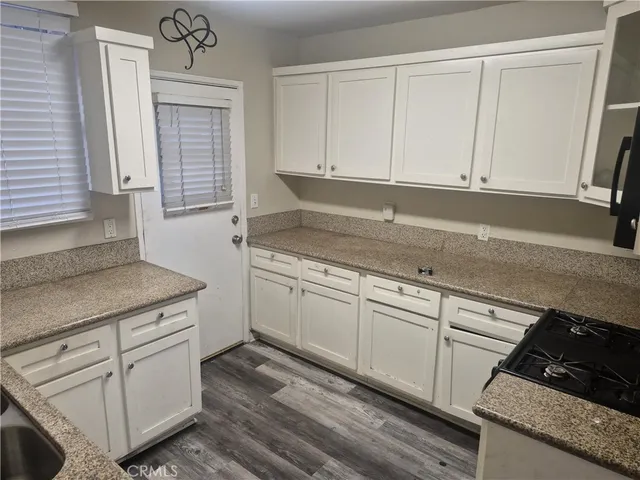a kitchen with granite countertop white cabinets and white appliances