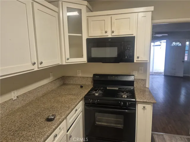 a kitchen with granite countertop a stove and a microwave