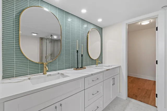 a bathroom with a double vanity sink mirror and bathtub