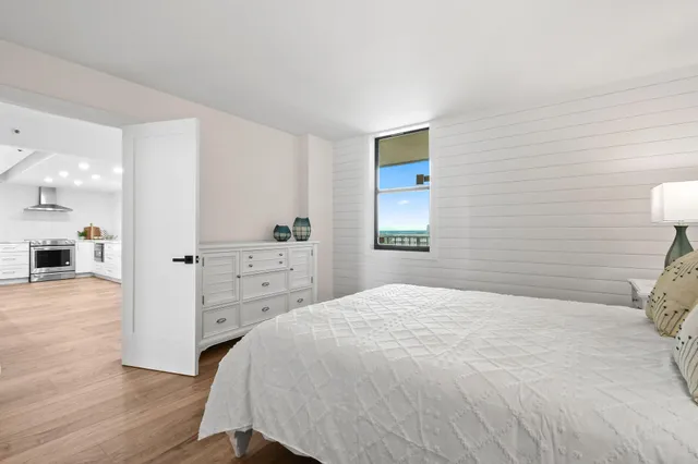 a spacious bedroom with a bed and a view of kitchen