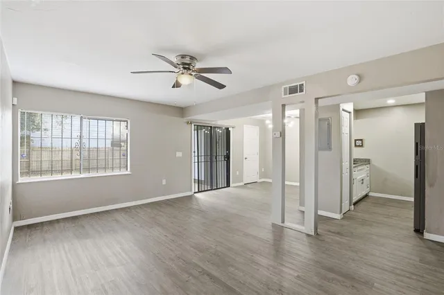 a view of empty room with wooden floor and fan