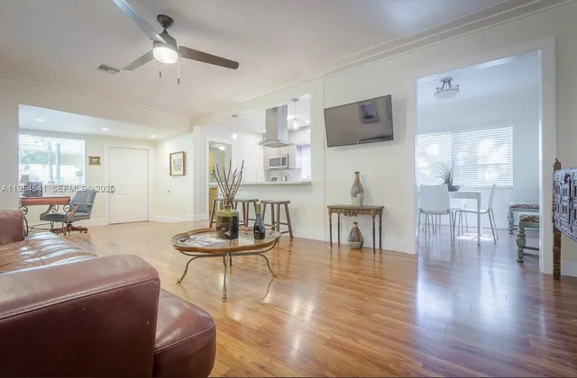 a living room with furniture kitchen view and a wooden floor