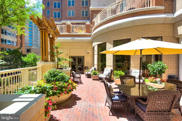 a view of a patio with couches table and chairs under an umbrella