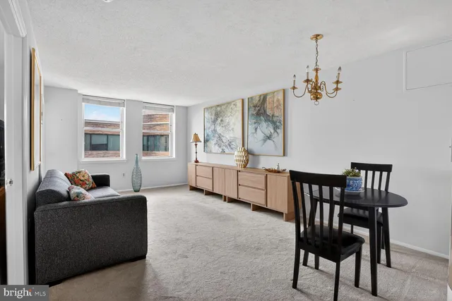 a living room with furniture and a dining table with projector the kitchen