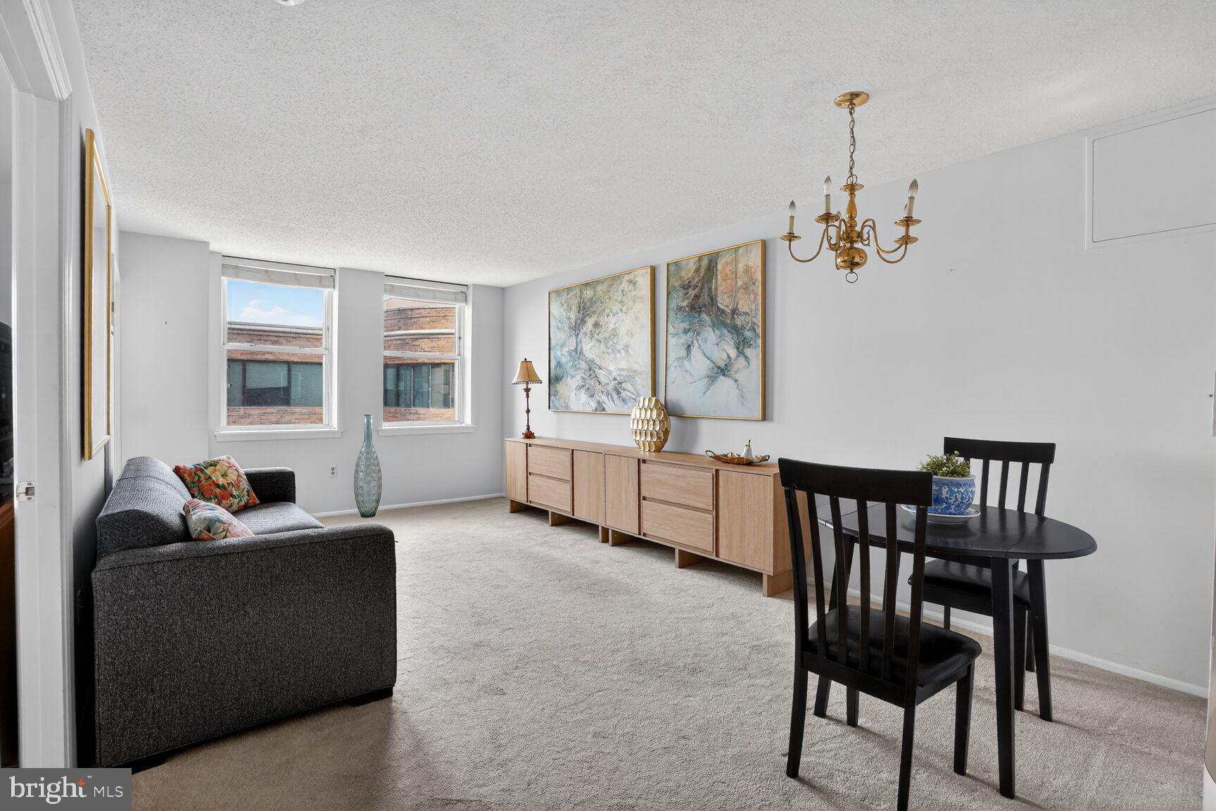 900 North Taylor Street, Unit 909 Arlington, VA 22203 - Photo 8 of 42 a living room with furniture and a dining table with projector the kitchen