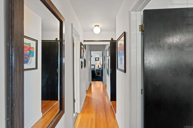a view of a hallway with wooden floor and living room