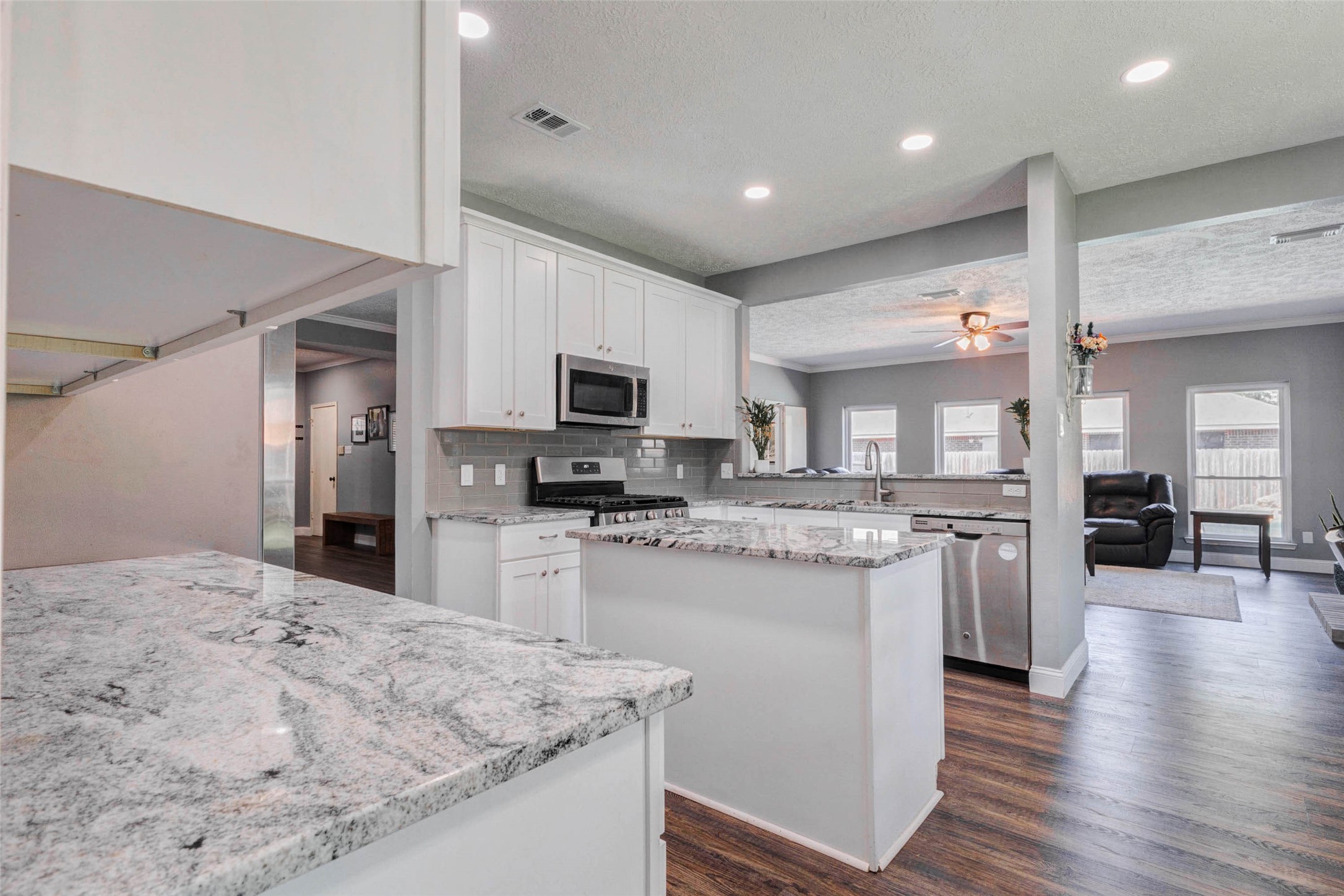 9215 Landry Boulevard Spring, TX 77379 - Photo 13 of 42 Wrap around white cabinetry, recessed lighting, wood look flooring, and expansive granite countertops create a bright and functional kitchen.