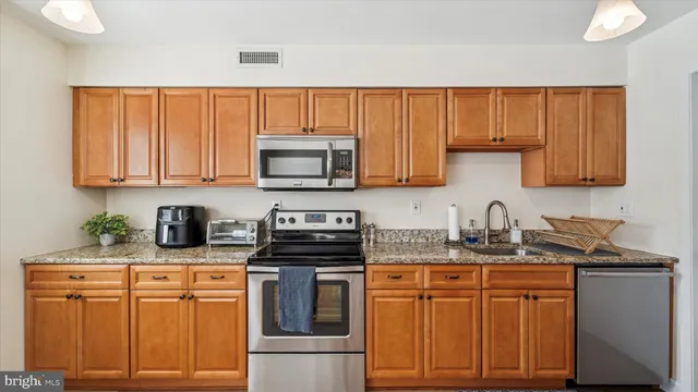 a kitchen with stainless steel appliances granite countertop a stove a sink dishwasher and a microwave oven with cabinets